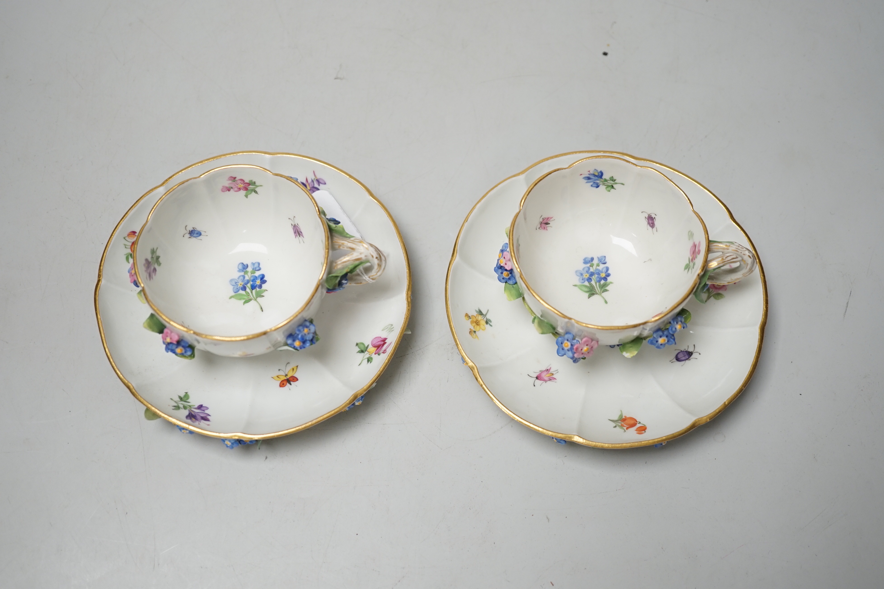 A pair of Meissen floral-encrusted cabinet cups and saucers, late 19th century, saucers 14cm diam.